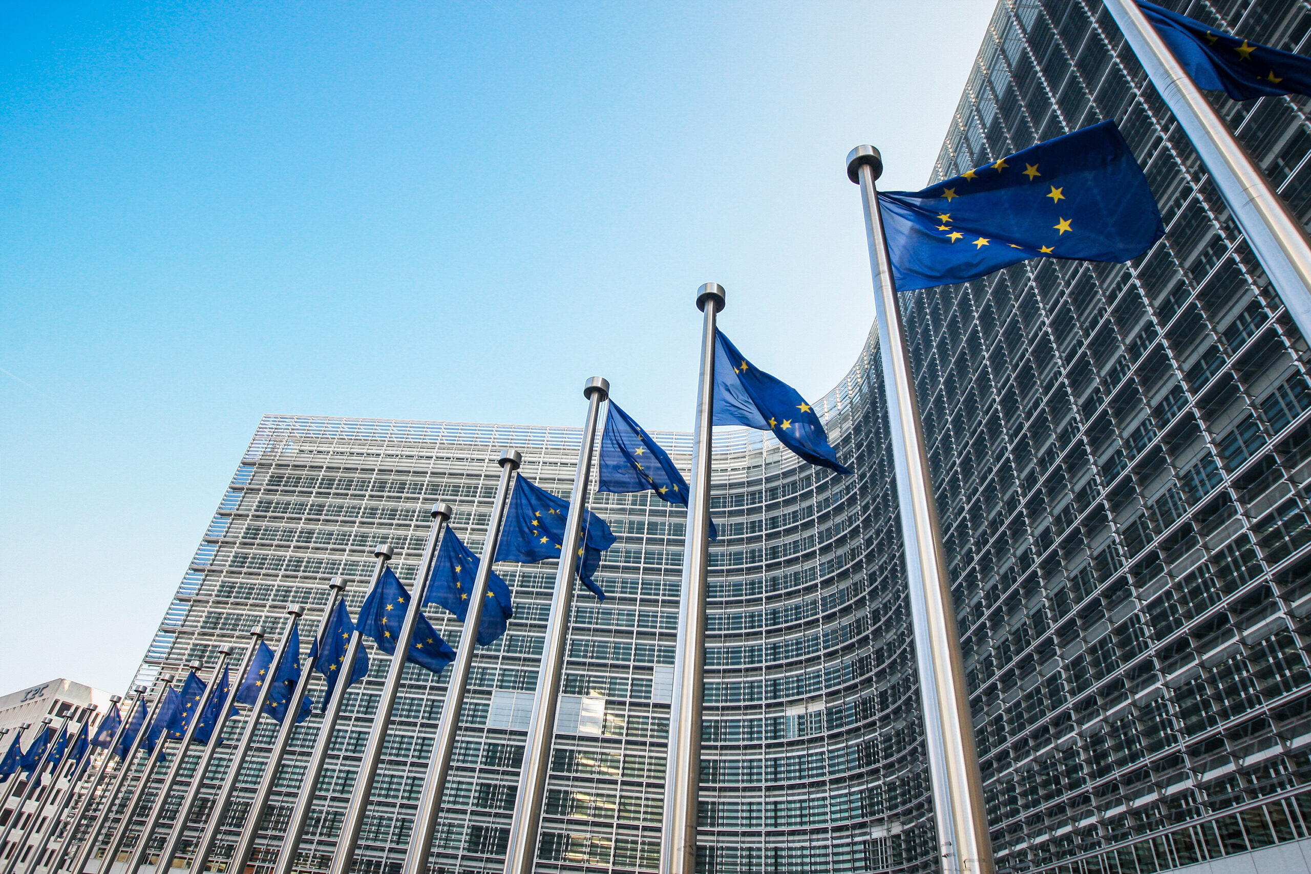 Das Bild zeigt die Flaggen der Europäische Union vor Glasfassade der Europäischen Kommission