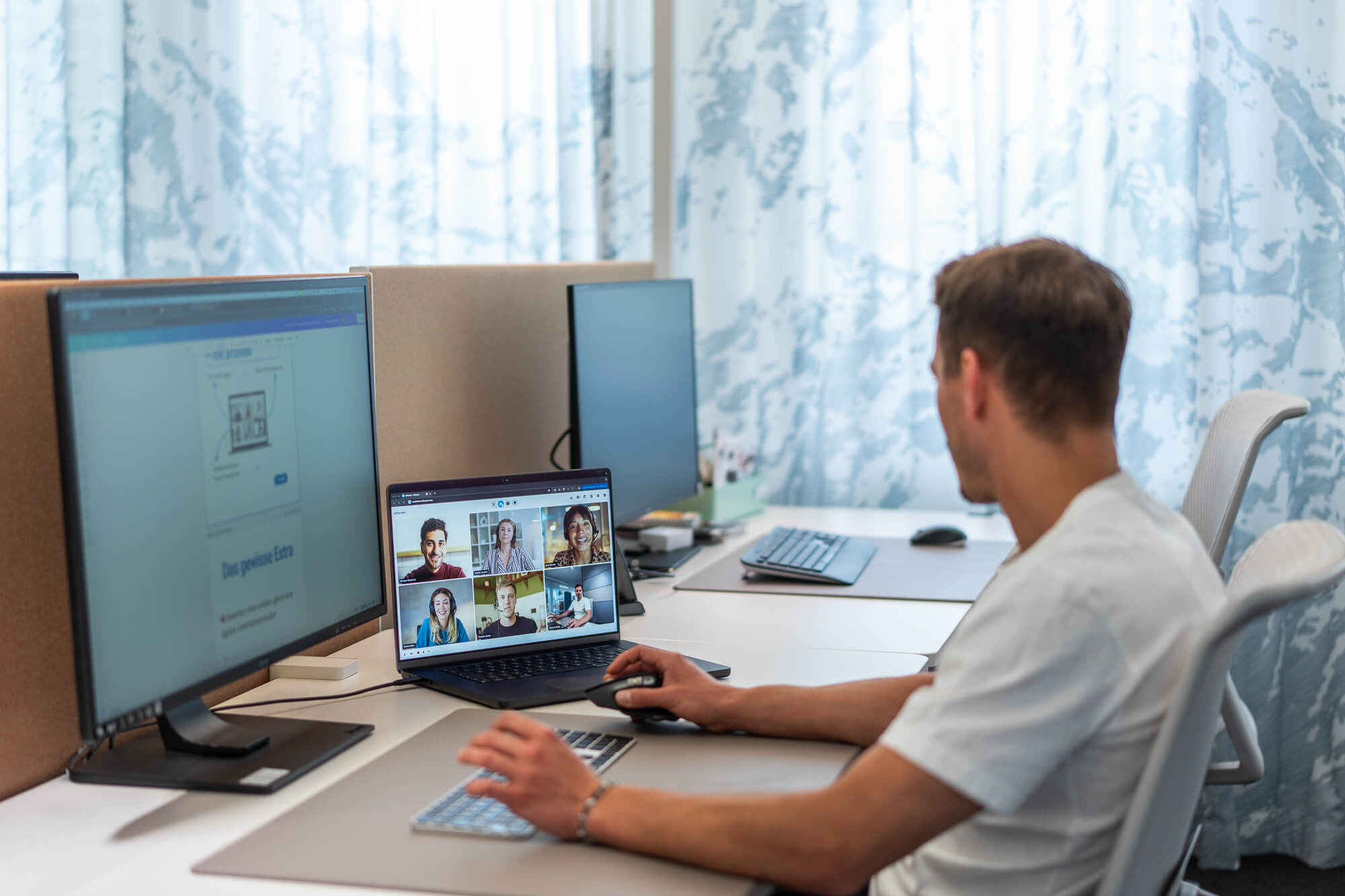 Mann sitzt am Schreibtisch und nimmt an einer Videokonferenz teil.