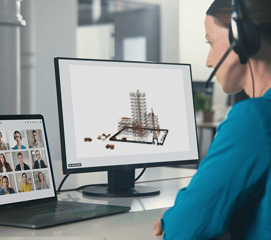 Person mit Headset arbeitet am Computer und betrachtet ein 3D-Modell auf dem Bildschirm, daneben läuft eine Videokonferenz.
